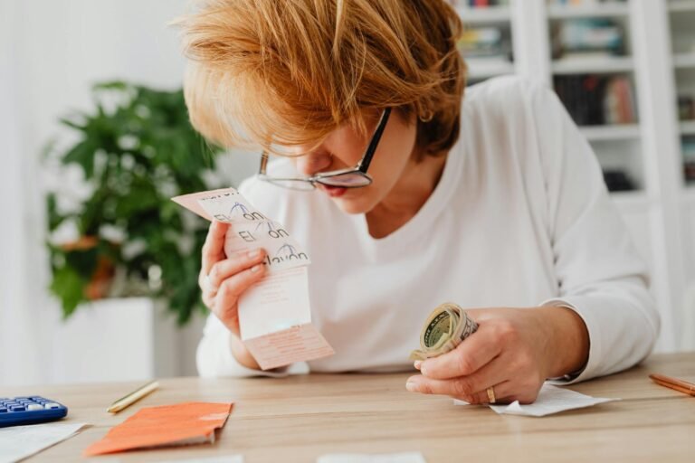 A woman sitting at a desk, reviewing bills and cash, symbolizing financial planning and management.